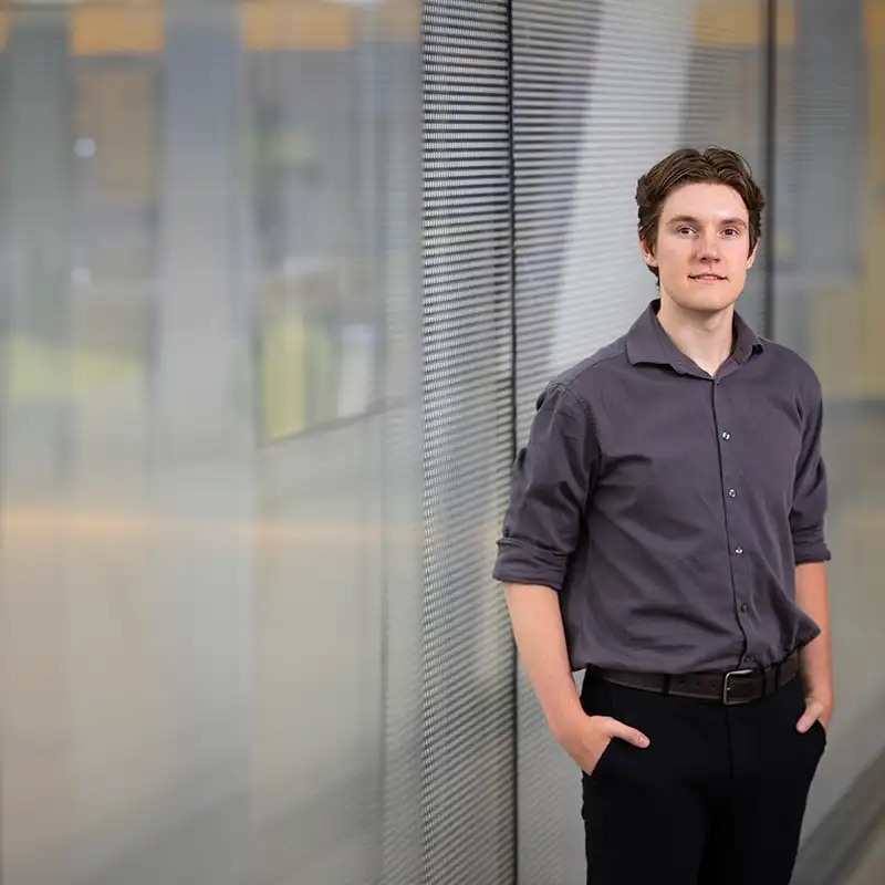 Image of Caden Kjelgren sanding next to a glass partition in an office