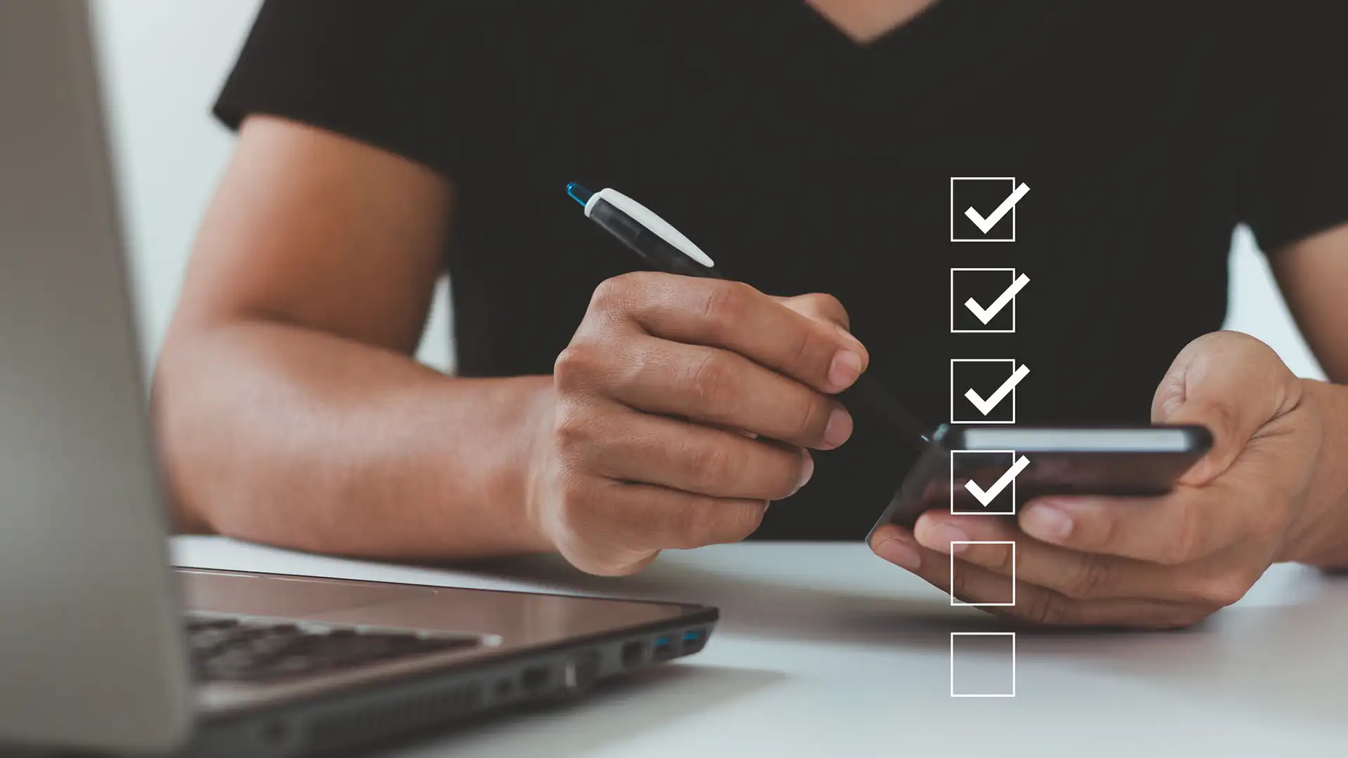 A man running a series of checks using a phone and a laptop