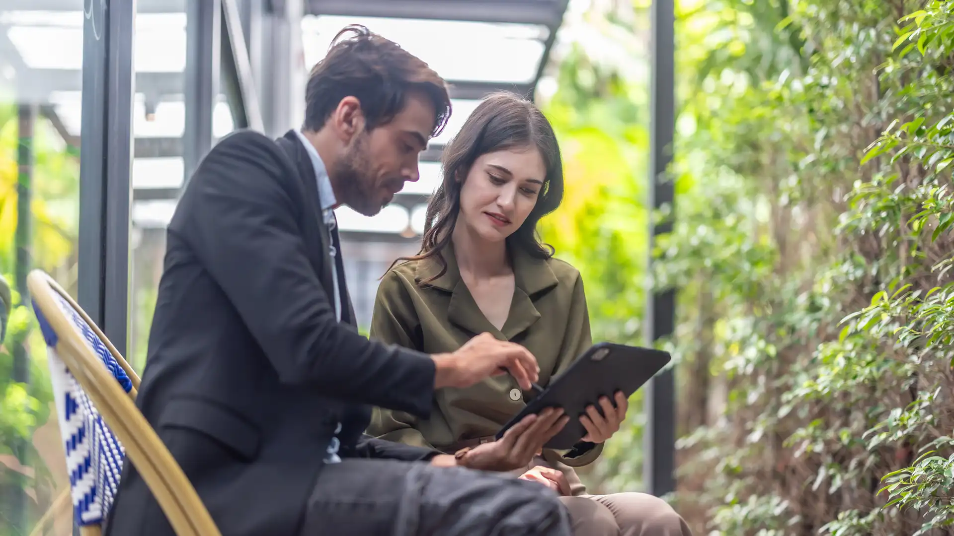 Two colleagues reviewing statistical information in a leafy environment